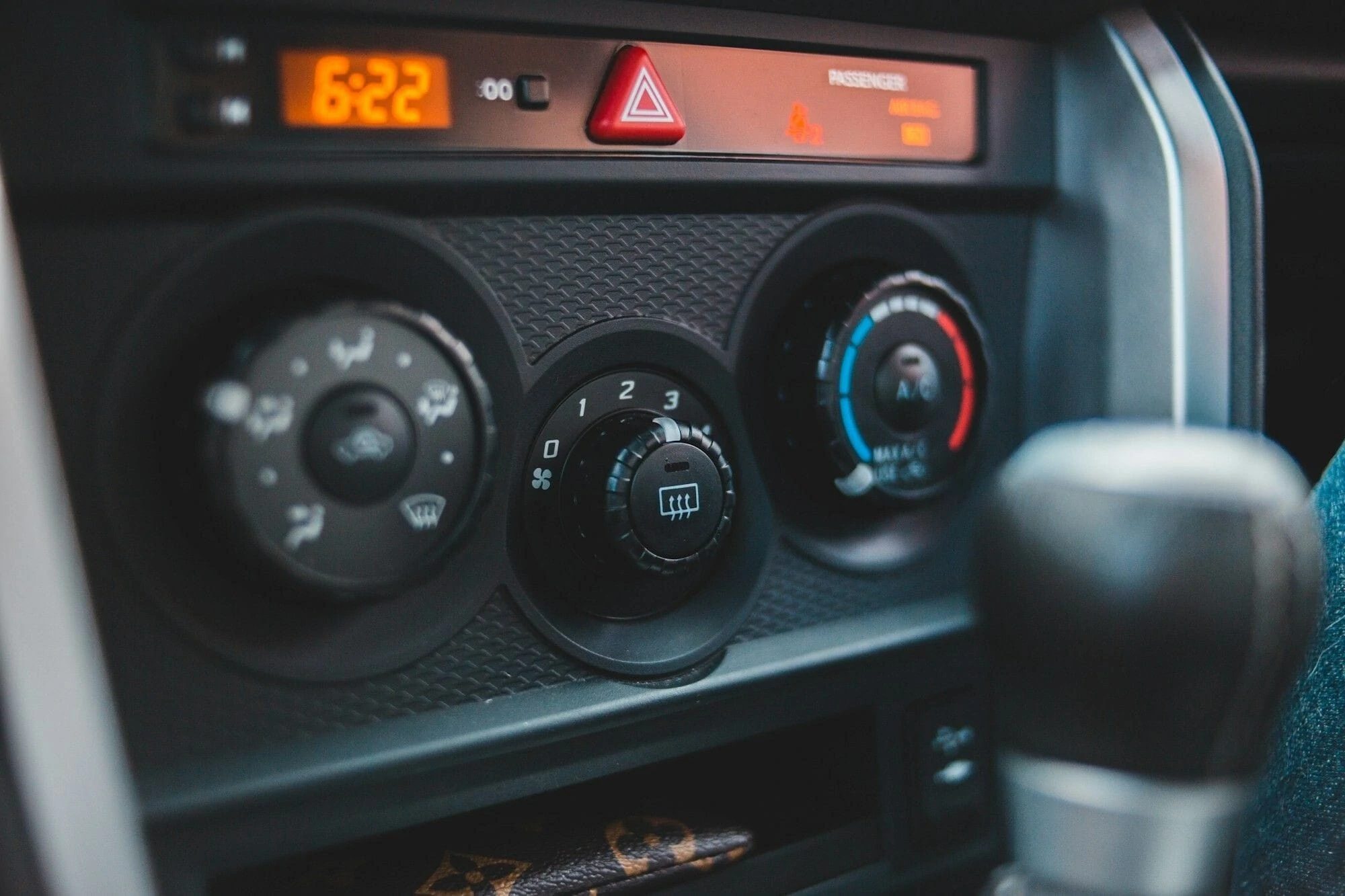 Close-up of a vehicle dashboard climate control panel with fan, temperature and demist dials