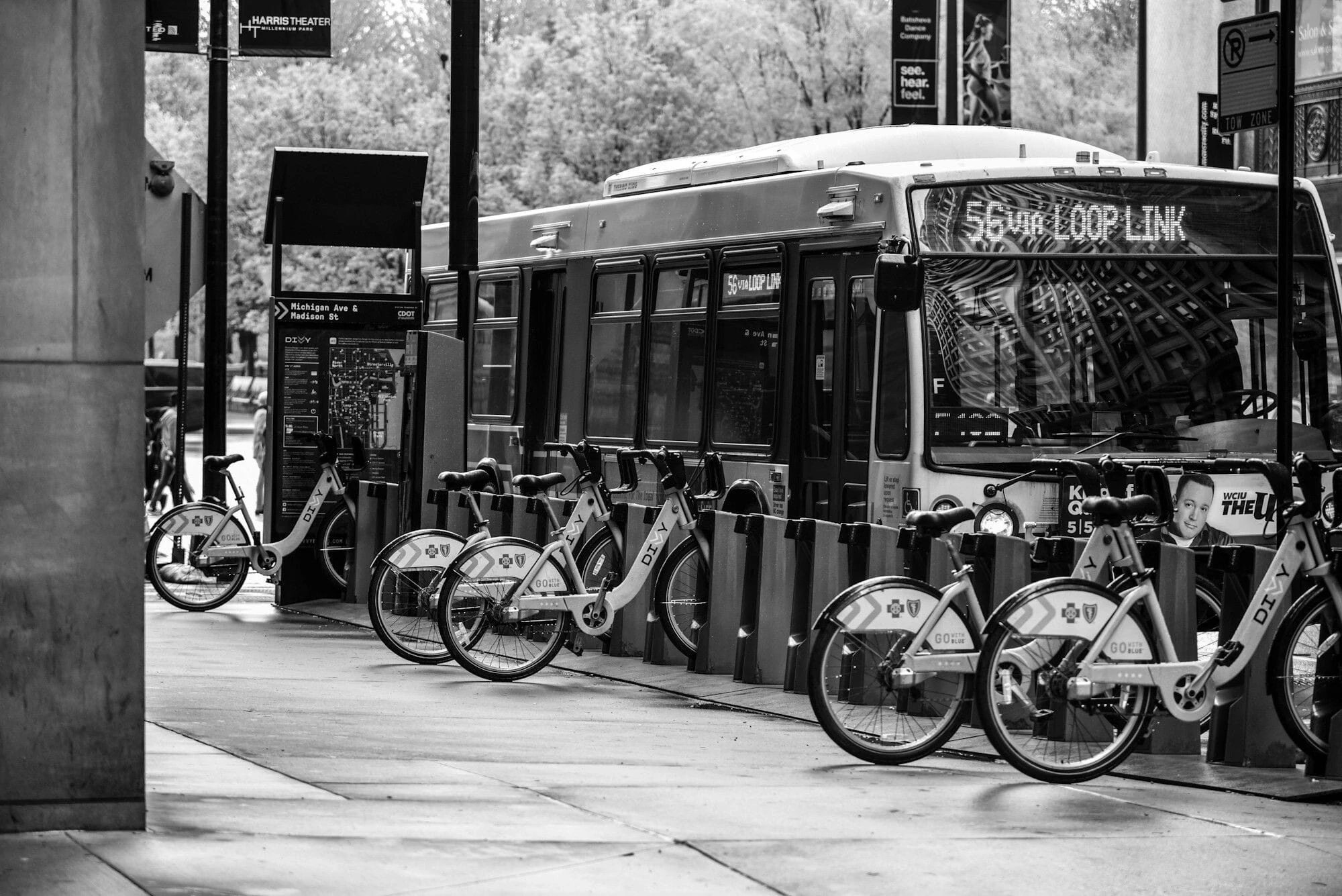 A city route bus waiting at a kerbside stop, in black and white