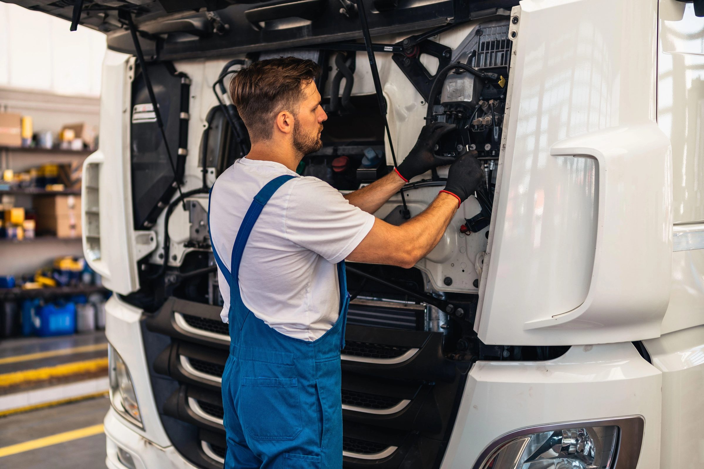 A technician inspecting the open front panel of a white truck cab